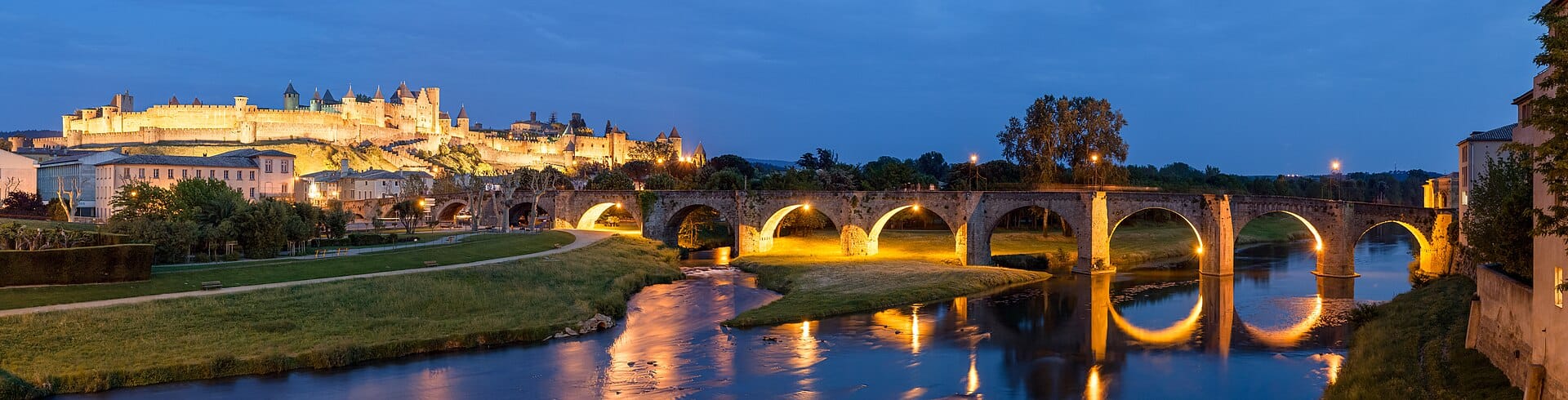 Le Pont Vieux illuminé à la tombée de la nuit, avec la Cité de Carcassonne en arrière-plan